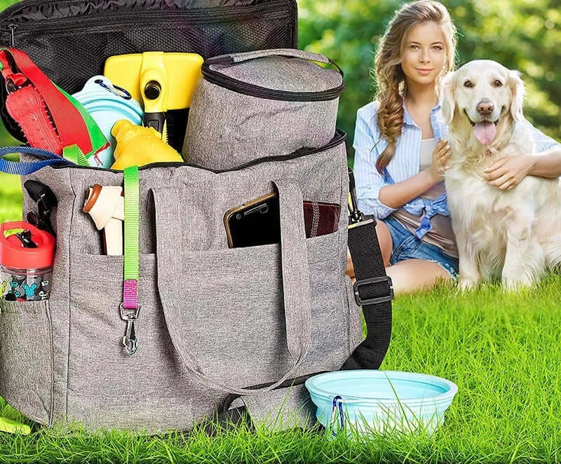 Pet travel bag with organized compartments beside a woman and her golden retriever in a grassy outdoor setting.