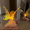 Load image into Gallery viewer, Dog wearing electric light-up butterfly wings looking in a mirror, showcasing a stylish and adjustable pet costume.
